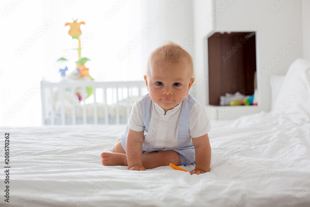 Happy baby eating carrot. Healthy nutrition for kids. Bio carrot as first solid food for infant Happy baby eating carrot. Healthy nutrition for kids. Bio carrot as first solid food for infant