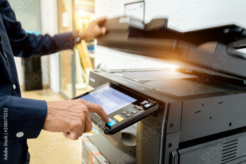 Fotografie, Obraz Bussiness man Hand press button on panel of printer, printer scanner laser office copy machine supplies start concept