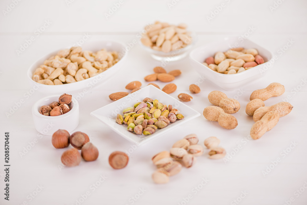 variety, mixture of different nuts on white background in white bowls variety, mixture of different nuts on white background in white bowls