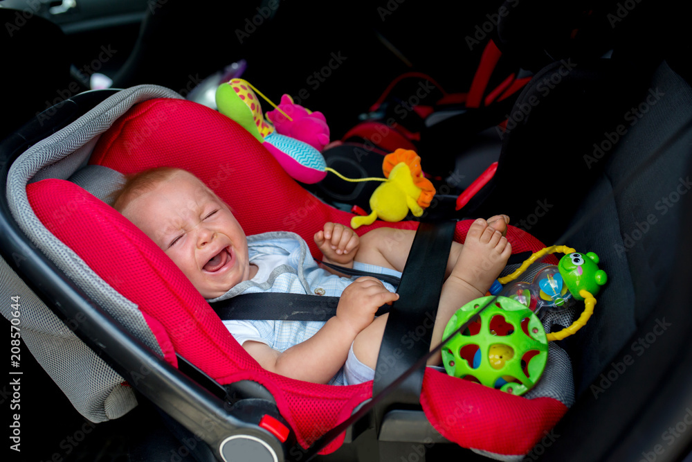 Little baby boy crying in the car, in car seat, child not wanting to travel. ภาพถ่ายสต็อก