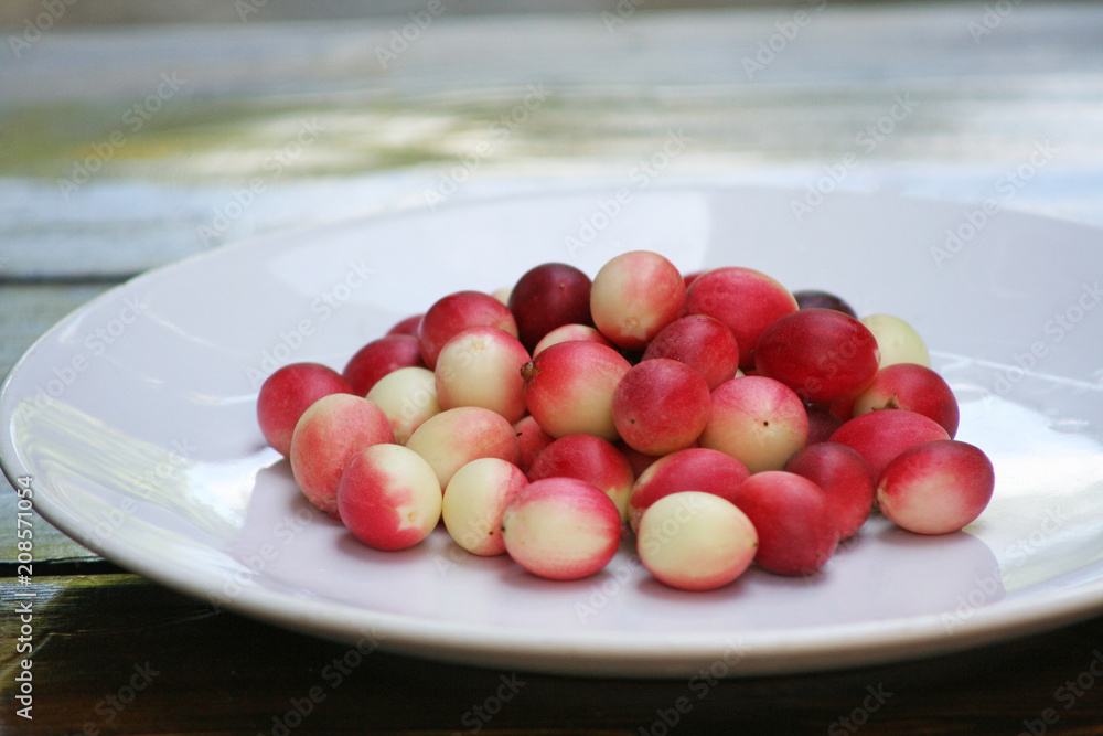 Red karonda on white plate on table background Red karonda on white plate on table background