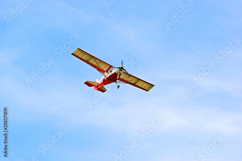 Small red airplane on a background of blue sky.