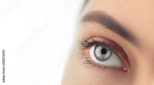 Fototapeta Naklejka Na Ścianę i Meble -  Young woman blue eye closeup. Macro eye looking up, isolated on white background