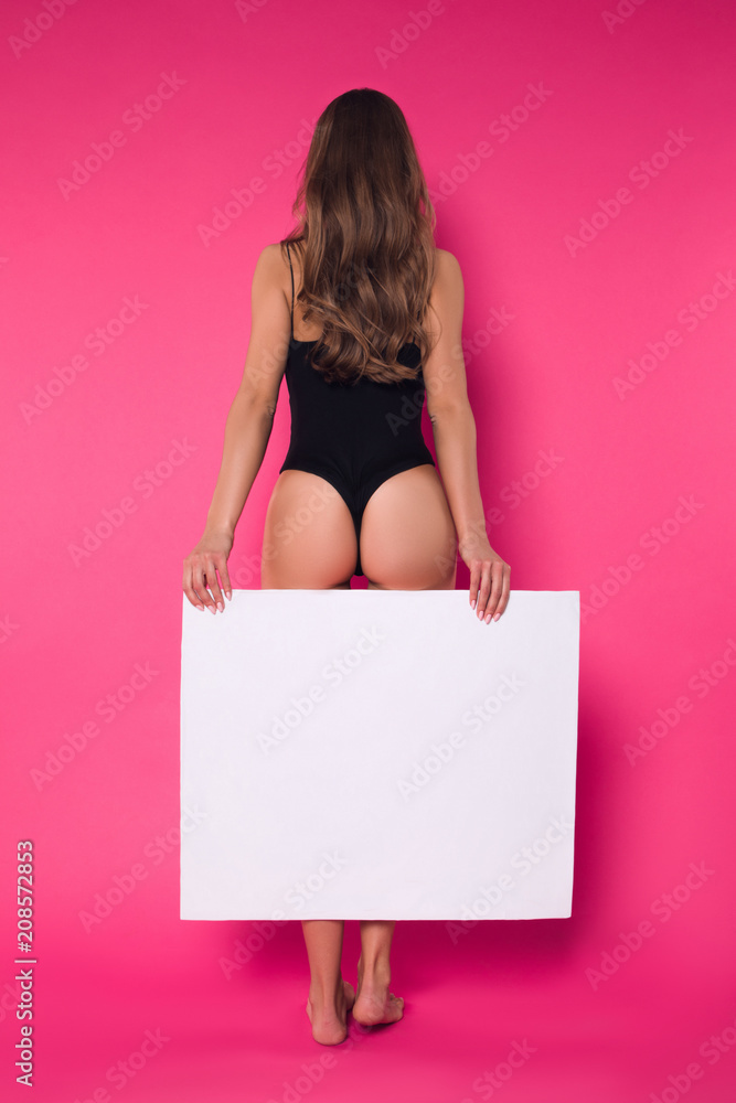 Create your own style! Trendy good-looking lady in the wonderful fit in sexy lingerie standing with her back to the camera, while posing for photo with blank board. Create your own style! Trendy good-looking lady in the wonderful fit in sexy lingerie standing with her back to the camera, while posing for photo with blank board.