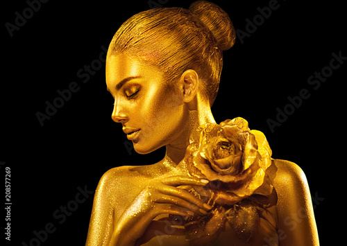 Golden skin woman with rose. Fashion art portrait. Model girl with holiday golden glamour shiny professional makeup. Gold jewellery, accessories