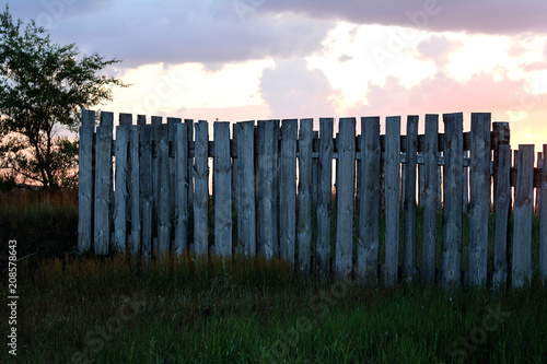 Wooden fence against the background of the evening sky with a contour light.