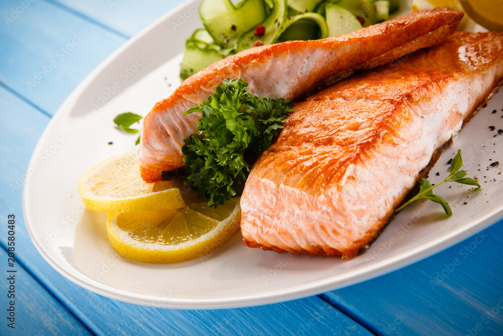 Grilled salmon with vegetables on blue wooden table Grilled salmon with vegetables on blue wooden table