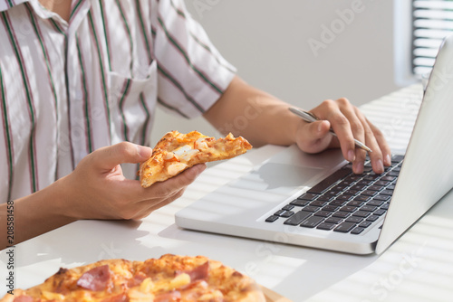 Eating pizza and social networking with a laptop.