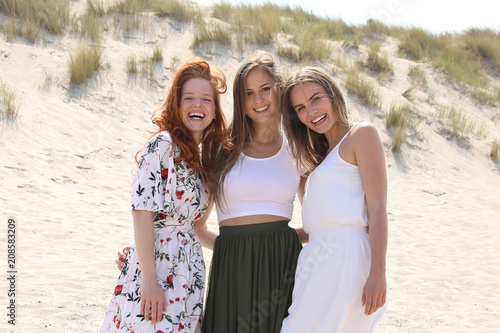 Drei hübsche Frauen stehen lachend an einem Strand