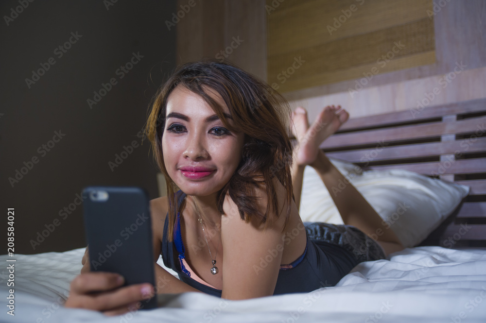 young beautiful and happy woman lying on bed smiling and flirting on internet social media app using mobile phone cheerful and relaxed on her bedroom young beautiful and happy woman lying on bed smiling and flirting on internet social media app using mobile phone cheerful and relaxed on her bedroom