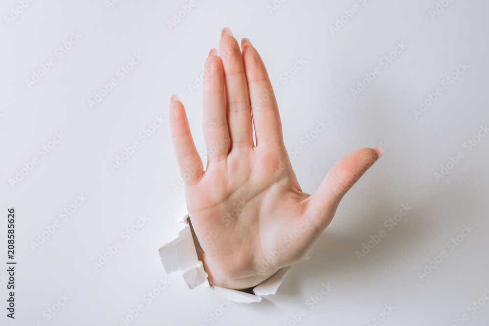 Naklejka premium girl hand breaks white paper and shows a gesture