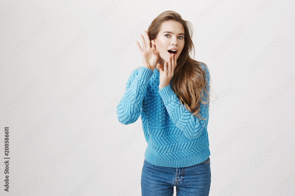 Studio portrait of intrigued european woman who likes to gossip, bending towards camera with hands near ear and opened mouth, being shocked with what she heard while eavesdropping or listening rumor Studio portrait of intrigued european woman who likes to gossip, bending towards camera with hands near ear and opened mouth, being shocked with what she heard while eavesdropping or listening rumor
