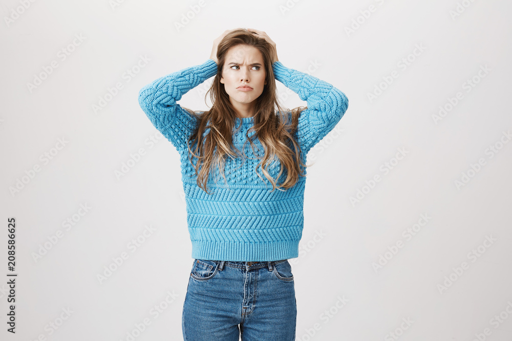 Indoor shot of clueless determined caucasian woman holding hands on head and looking up with puzzled expression as if she thinks or forgot something, standing over gray background. Did I closed door Indoor shot of clueless determined caucasian woman holding hands on head and looking up with puzzled expression as if she thinks or forgot something, standing over gray background. Did I closed door