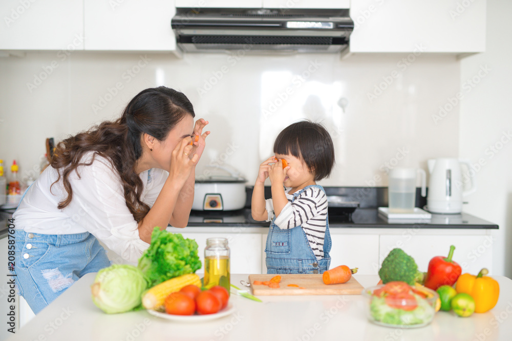 Mother with her daughter in the kitchen cooking together Mother with her daughter in the kitchen cooking together