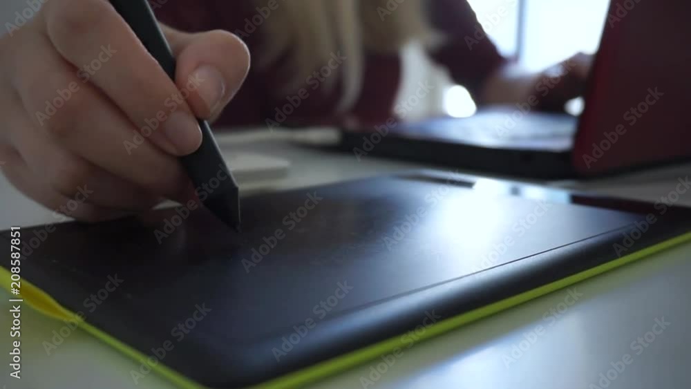Close up female hand using stylus graphic tablet board at her office Close up female hand using stylus graphic tablet board at her office
