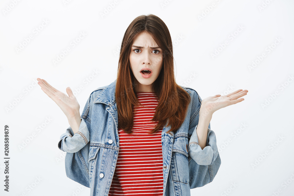 What do you want from me. Portrait of angry fed up cute girlfriend in denim  jacket, spreading raised palms and frowning, arguing with friend, being  frustrated and confused over gray background Stock-Foto