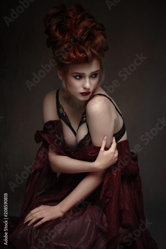 Portrait of woman with baroque hairstyle and fancy lace lingerie posing on dark background