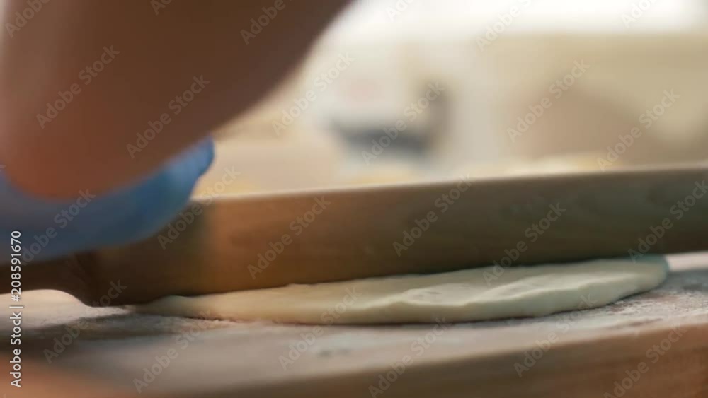 Hand baker rolling dough on table for baking pie in restaurant close up Hand baker rolling dough on table for baking pie in restaurant close up