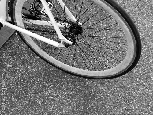 Speichenrad eines weißen Fahrrad vor grauem Asphalt im Sommer auf dem Campus der Universität in der Hansestadt Hamburg, fotografiert in klassischem Schwarzweiß photo