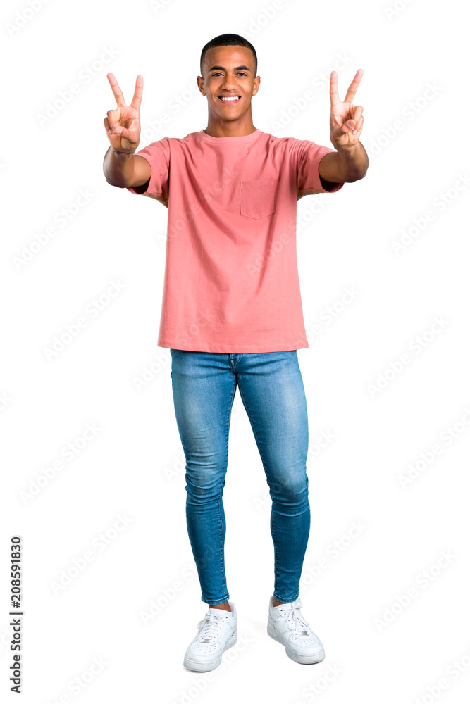 Standing young african american man smiling and showing victory sign with both hands and with a cheerful face on isolated white background Standing young african american man smiling and showing victory sign with both hands and with a cheerful face on isolated white background