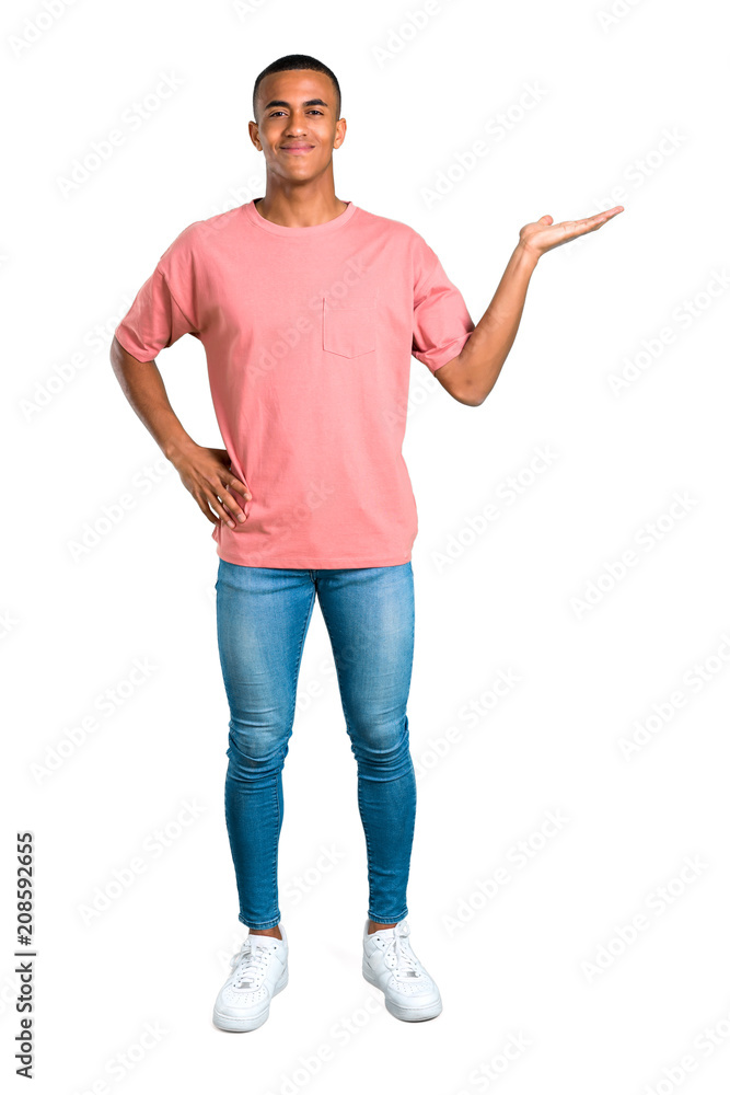Standing young african american man holding copy space imaginary on the palm to insert an ad on isolated white background Standing young african american man holding copy space imaginary on the palm to insert an ad on isolated white background