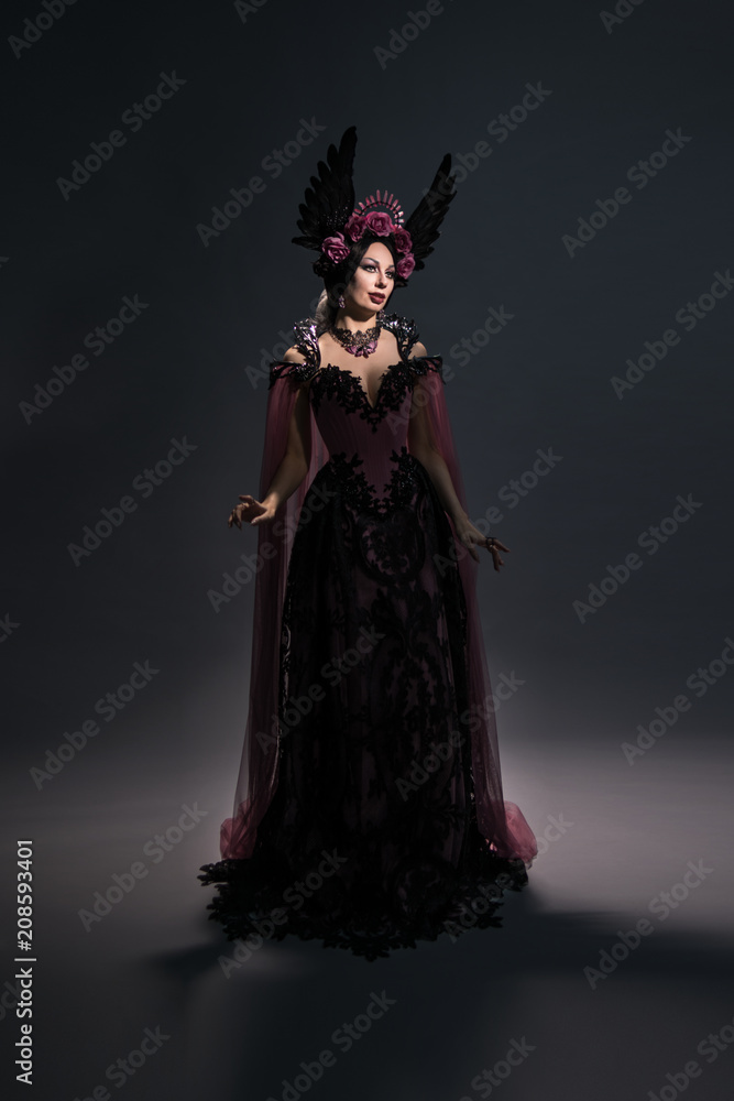 Full length view of charming brunette woman in rose crown posing on dark background