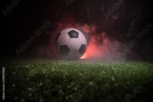 Traditional soccer ball on soccer field. Close up view of soccer ball (football) on green grass with dark toned foggy background. © zef art