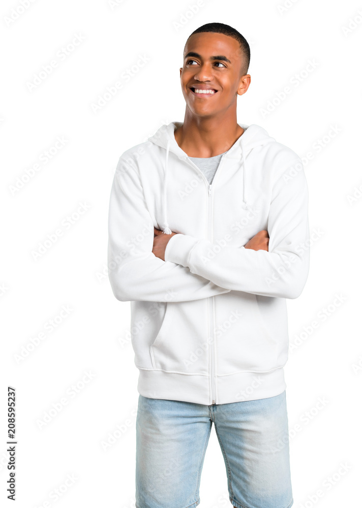 Dark-skinned young man with white sweatshirt stand and looking up while smiling on isolated white background Dark-skinned young man with white sweatshirt stand and looking up while smiling on isolated white background