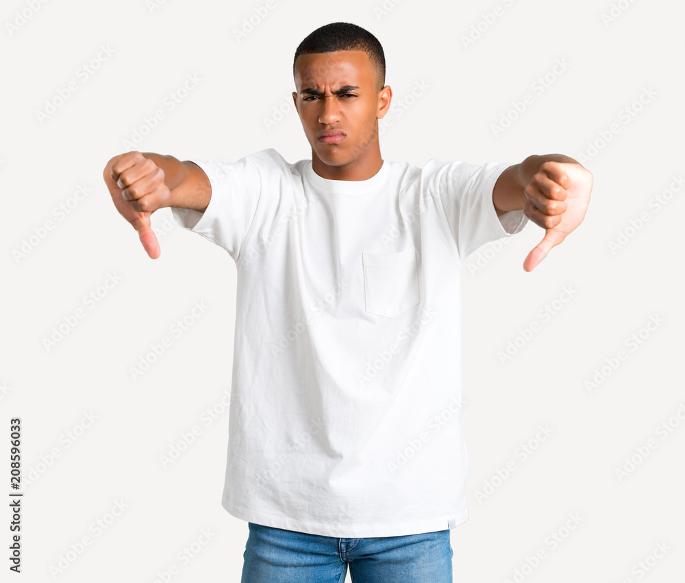 Young african american man showing thumb down with both hands. Negative expression on isolated background Young african american man showing thumb down with both hands. Negative expression on isolated background