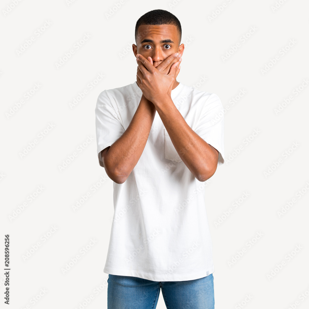 Fototapeta premium Young african american man covering mouth with both hands for saying something inappropriate. Can not speak on isolated background