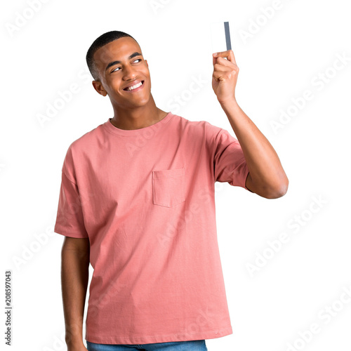 Young african american man holding a credit card and thinking on isolated white background