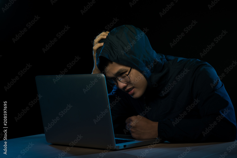 Hacker in a dark hoody sitting in front of a notebook. Computer privacy attack Hacker in a dark hoody sitting in front of a notebook. Computer privacy attack