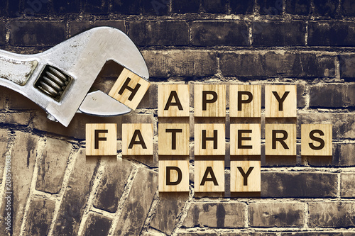 Happy Fathers Day inscription on wooden cubes with working tools on an old vintage brick wall. Happy Father's Day Concept. Greetings and gifts.