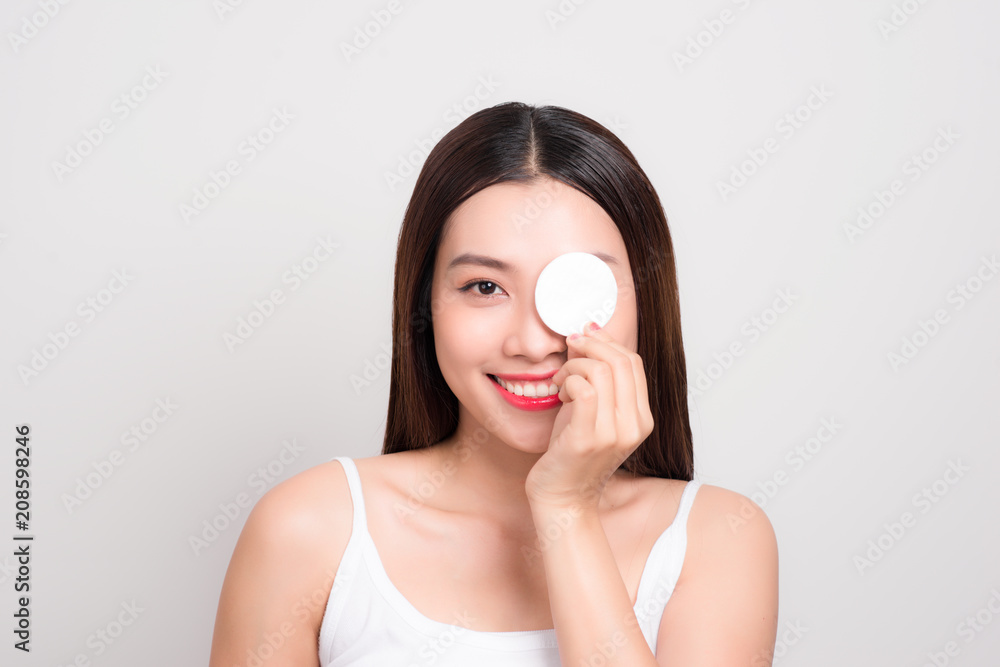 Beautiful asian woman with flawless skin is holding cotton pads on hand cover her eyes. Beautiful asian woman with flawless skin is holding cotton pads on hand cover her eyes.
