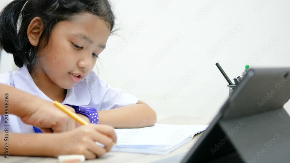 4K Asian little girl in Thai student uniform doing homework on wooden table select focus shallow depth of field 4K Asian little girl in Thai student uniform doing homework on wooden table select focus shallow depth of field