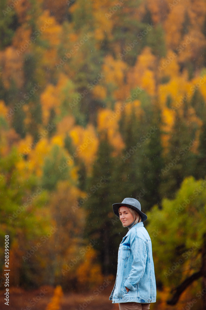 Beautiful young woman in hat on autumn forest background. Landscape in autumn. Beautiful young woman in hat on autumn forest background. Landscape in autumn.
