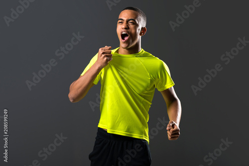 Soccer player man with dark skinned playing celebrating victory on dark background