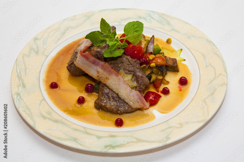 Meat with tomatoes and greens cooked on a plate Meat with tomatoes and greens cooked on a plate