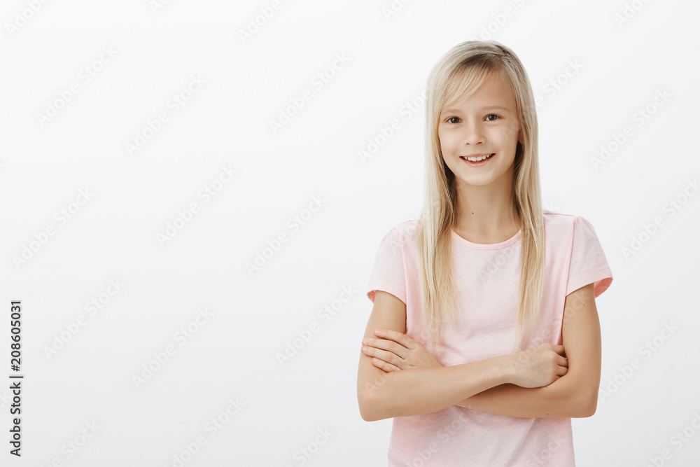 Portrait of happy cute little girl smiling broadly, holding hands crossed over chest and feeling confident, knowing what she talking about, self-assured about homework, presenting project to parents Portrait of happy cute little girl smiling broadly, holding hands crossed over chest and feeling confident, knowing what she talking about, self-assured about homework, presenting project to parents