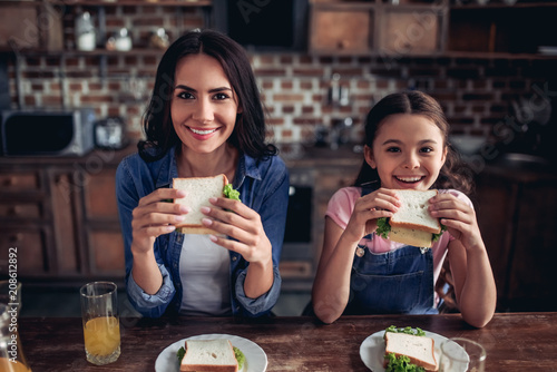 mother and daughter eating sandwiches