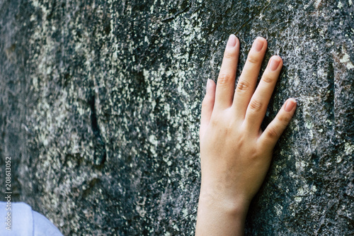 The hand of a girl touching a rock.