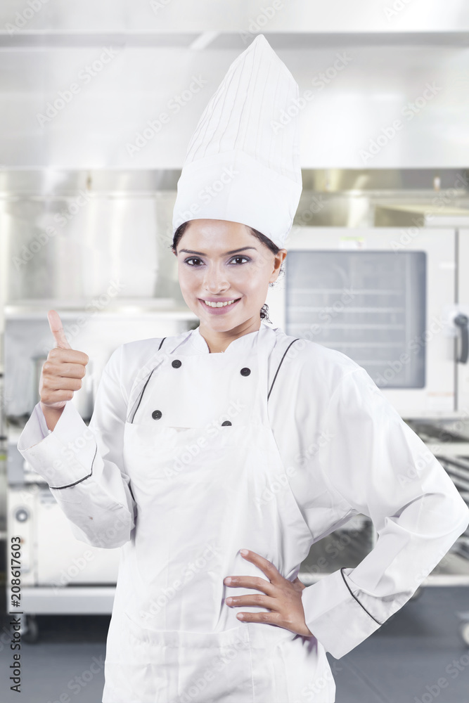 Female chef showing thumb up in the kitchen Female chef showing thumb up in the kitchen