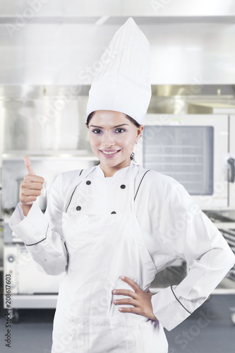 Female chef showing thumb up in the kitchen