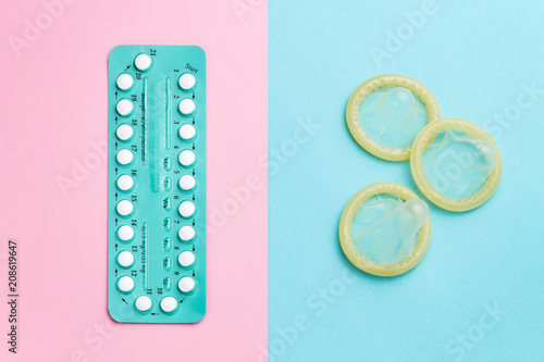 фотографія Contraceptive pills and condoms on colored background