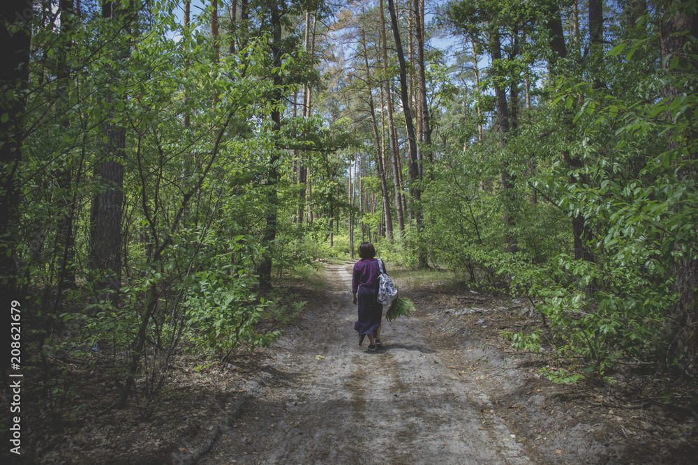 Girl walking in coniferous forest at summer.