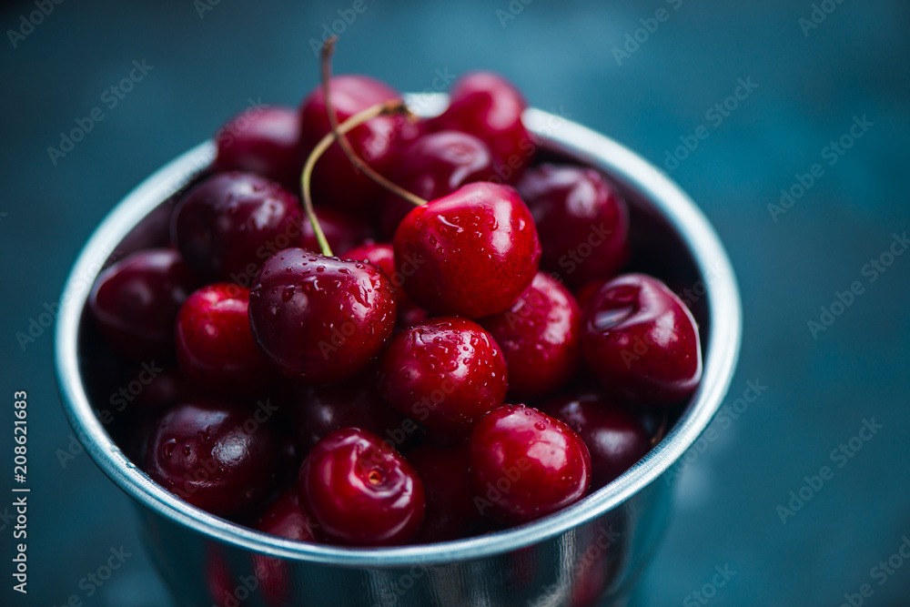 Cherries with a small metal bucket on a grey concrete background, summer berries concept with copy space. Neutral color tones still life