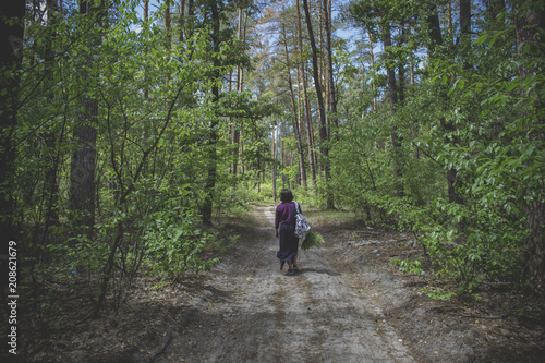 Girl walking in coniferous forest at summer.