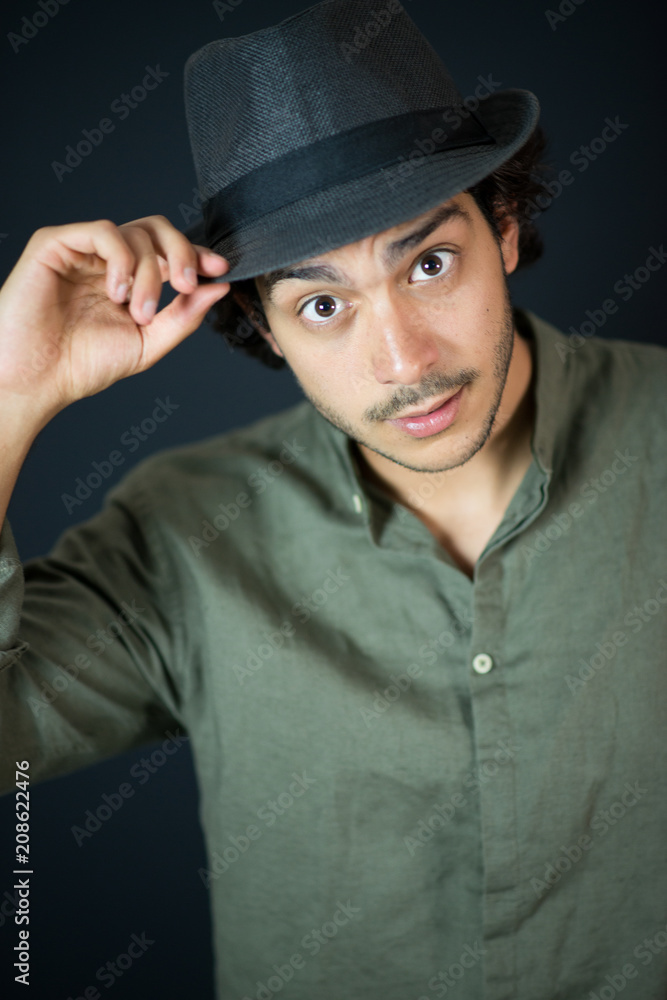 A nice young man, 20Y, is posing in studio with a hat. Black background. A nice young man, 20Y, is posing in studio with a hat. Black background.