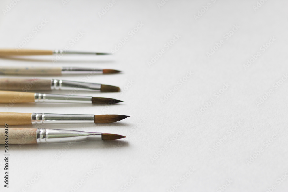 Several paintbrushes on a white paper background. Several paintbrushes on a white paper background.