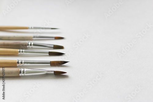 Several paintbrushes on a white paper background.